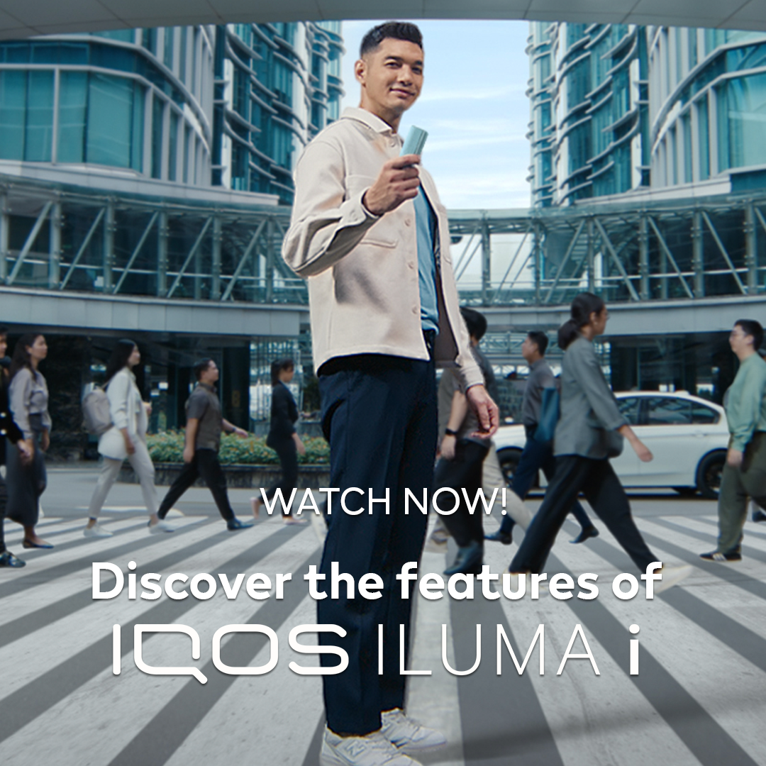 A person holding an IQOS Device in front of a building
